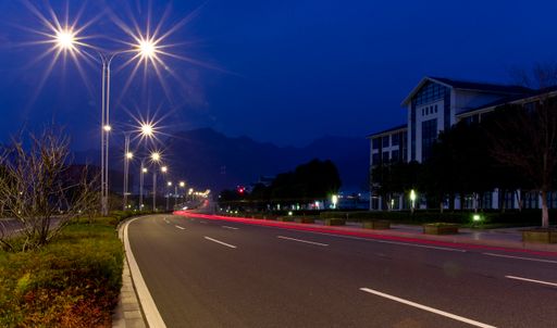 The view of the empty road at night with the red light trail.