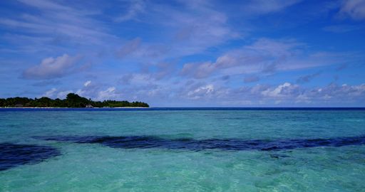 A calm blue ocean and a small island far away under the cloudy sky somewhere in Asia