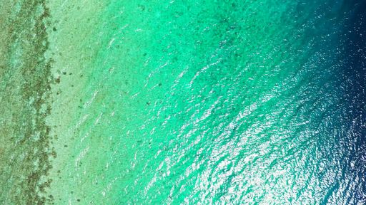 An aerial top view of a turquoise sea on a sunny day