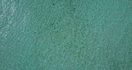 An aerial top view of a turquoise sea on a sunny day
