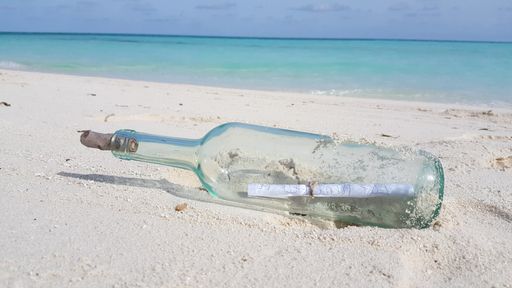 A closeup shot of a glass bottle with a message in it on the sand in the Maldives
