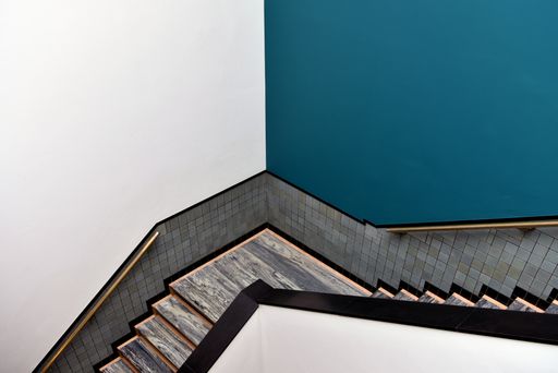A beautiful symmetric shot of a wooden staircase leading down with blue and white wallpaper