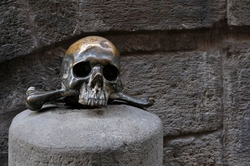 A closeup of a bronze skull in front of The Church of the Dead in Napoli, Naples, Italy