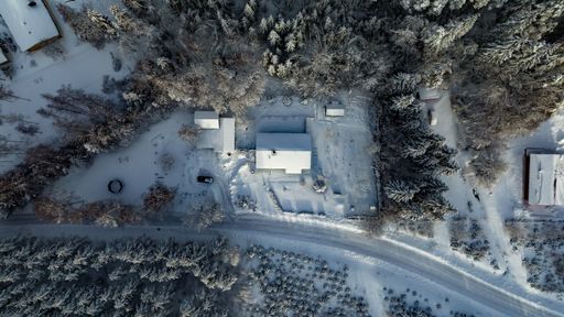 Aerial view above a snow covered house in middle of frosty forest - top down, drone shot