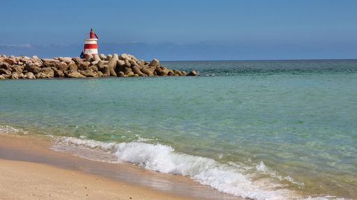 A lighthouse on sandy beach against the seascape under the blue sky of Tavira Island, Portugal