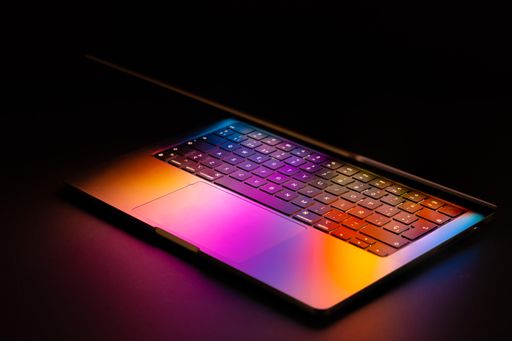 Spain, 03.20.2022: Macbook Pro 2021 with glowing colorful reflection on the keyboard and touchpad