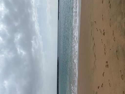 A vertical shot of a sandy and wavy beach on a cloudy day, Tenerife, Spain