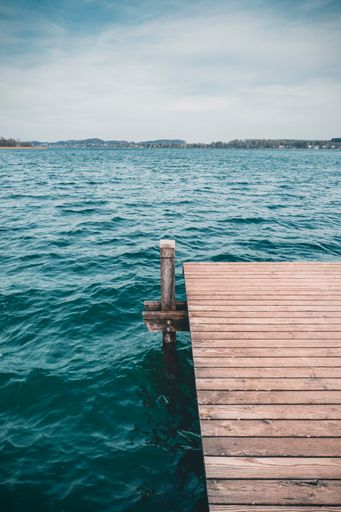 A vertical shot of a pier on a lake.