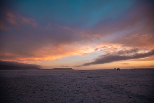 A scenic view of the beach in Cape Town and silhouettes of people standing farther at sunset