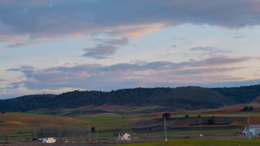 A beautiful view of a rural landscape with hills under the cloudy sunset sky