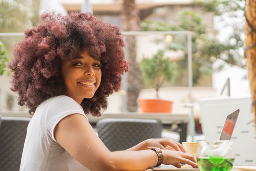 A young African American female in a coffee shop working online at her computer