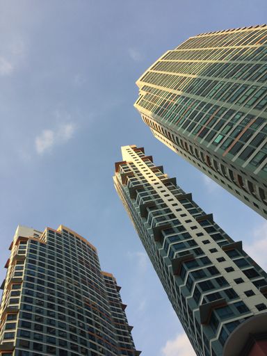 A vertical low angle shot of high-rise buildings under the blue sky