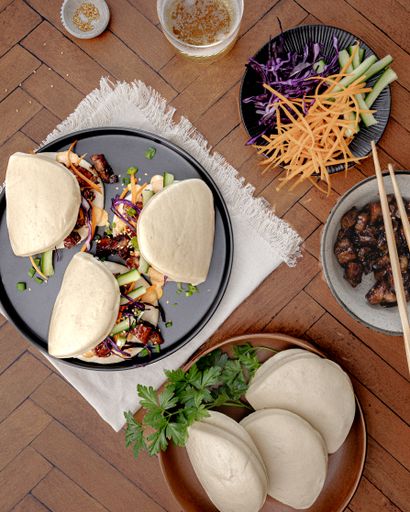 The delicious bao buns with veggies and pork belly served pm the table