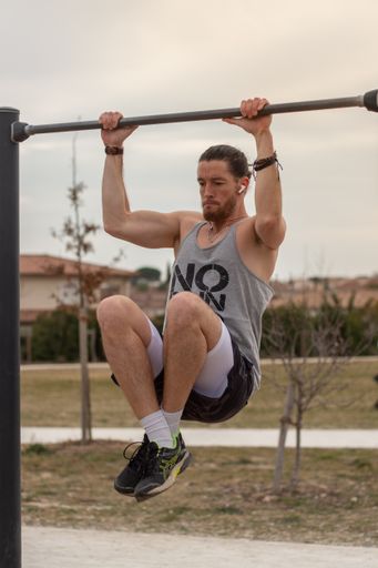 A Young Caucasian sportive man doing sports on a pull-up bar