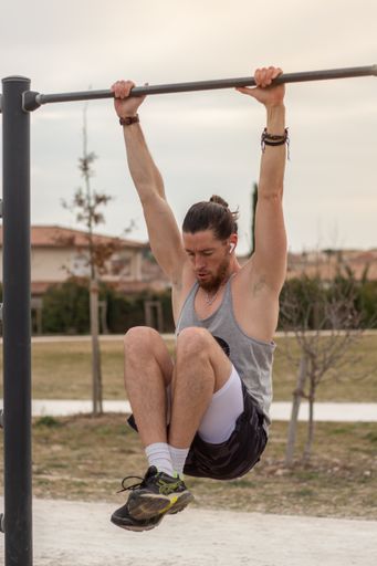 A young Caucasian sportive man doing sports on a pull-up bar