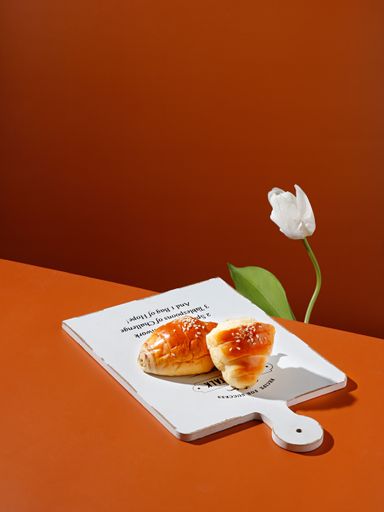 A vertical shot of croissants on white board near a white tulip flower