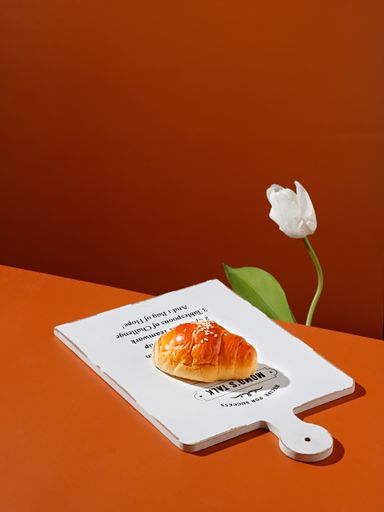The studio shot of a croissant served on a white wooden board with the orange background
