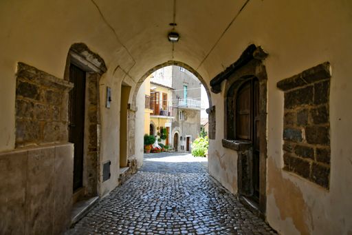 A vertical shot of a narrow alley between medieval stone buildings in Menza, Italy