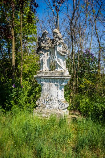 A beautiful shot of stone sculpture in the park surrounded by grass and trees in bright sunlight
