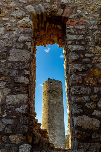 A beautiful vertical shot of a rocky arch shape on a medieval pole against a blue sunny sky