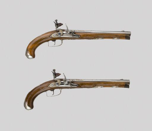 A top view of two old hand guns isolated on gray surface backg