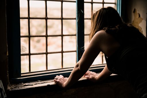 A woman with long hair looks out the window