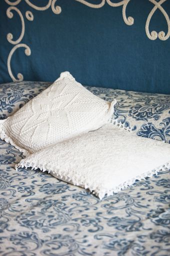 A vertical shot of white pillows on a bed with blue and white patterned sheets