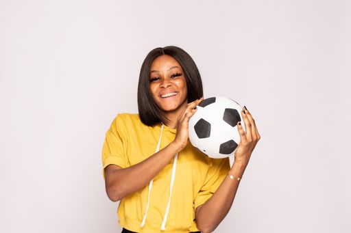 A closeup portrait of an excited African American young woman holding a soccer ball