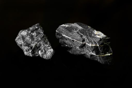 Macro Close up image of raw material Manganese Ore rock isolated on black reflective background