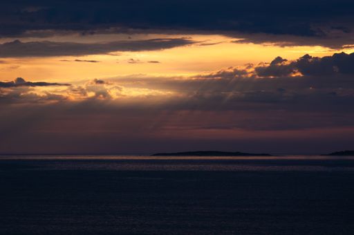 A scenic view of sunrays bursting through the clouds above the sea