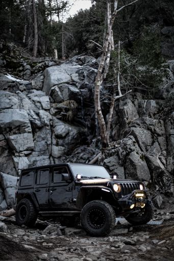 A vertical shot of a black Jeep Wrangler off-roading in the rocky hills of Riverside, US