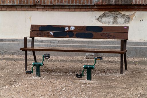 Madrid, Spain. March 18, 2022. Wooden bench with pedals in front to exercise the elderly, in a dirt area of a park.