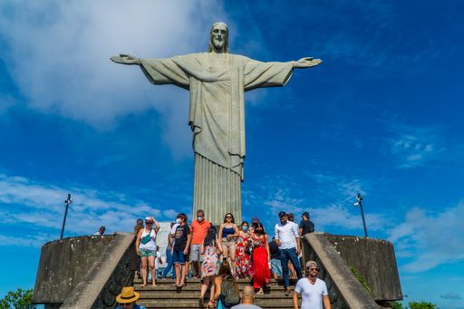 A low angle shot of tourists near Christ the Redeemer statue in a blue sky in Rio de Janeiro, Brazil