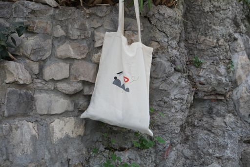 A low angle shot of a white eco-friendly shopping bag hanging on a wall
