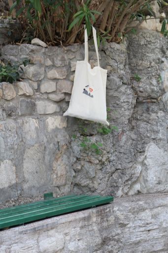 The white fabric tote bag hanging on a tree