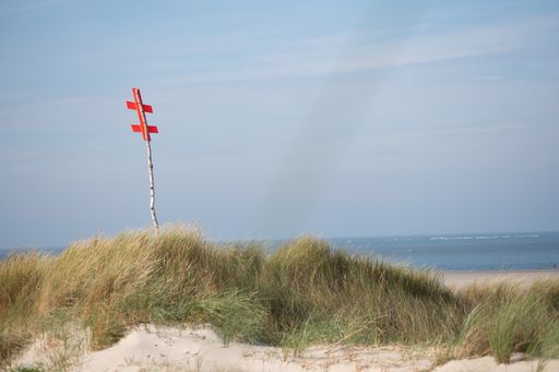 a photo of grass hill with red sign against beach