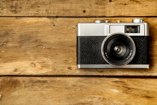 An overhead shot of a black vintage camera on a wooden surface
