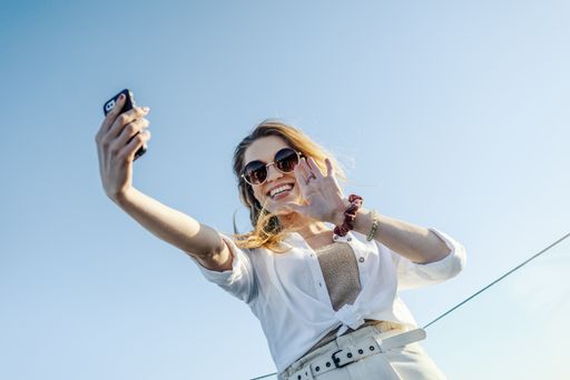 A young stylish woman with sunglasses and white shirt talking a selfie
