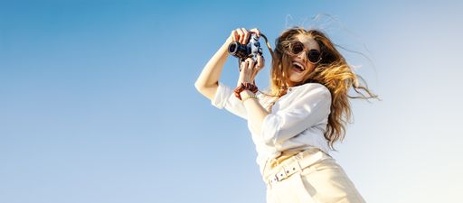 A young stylish woman with sunglasses and white shirt taking photos with the camera