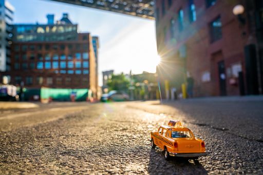 A selective focus shot of a toy of a taxi car on the street captured on a sunny day