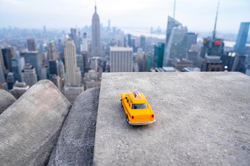 A closeup shot of a vintage taxi toy with New York cityscape on the background