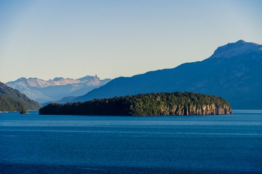 A scenic view of an island in the middle of the lake surrounded by mountains