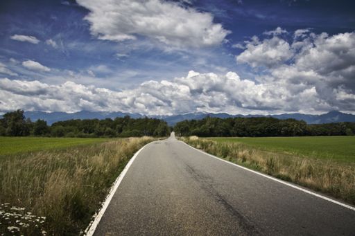 A mesmerizing scenery of the road among the beautiful landscape under a cloudy sky