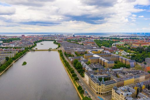 An aerial shot of a European city with a canal flowing through it under a cloudy sky