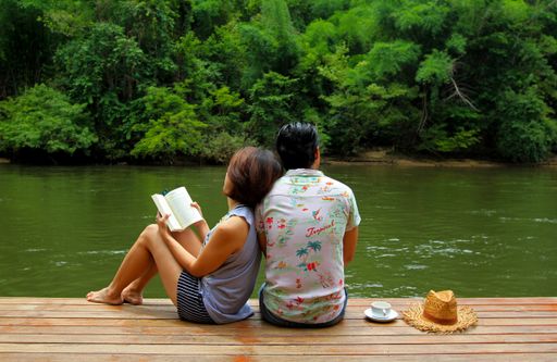 A happy couple sitting on the shore of the river - romantic concept