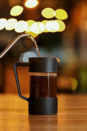 A vertical shot of hot water pouring into a French press