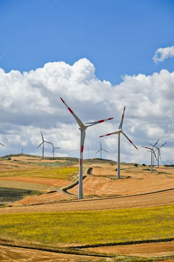 A vertical shot of the wind turbines against cloudy sky in the Apulian countryside in Italy