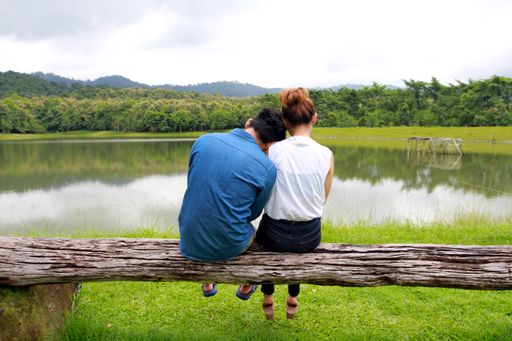 A romantic couple sitting on the wood and enjoying the view of a tranquil lake