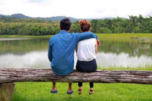 A romantic couple sitting on the wood and enjoying the view of a tranquil lake