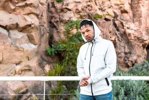 Handsome young African American man with dreadlocks hair against a background of rocks